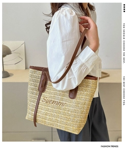 Detail of woven straw tote bag with brown leather handles and Suemmr embroidery