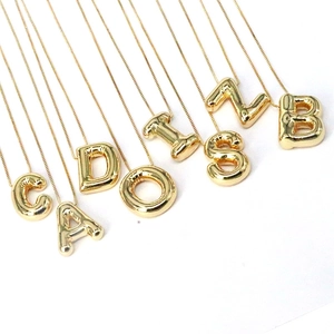Macro view of 3D balloon style gold alphabet pendants with polished mirror finish surface