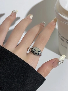 Close-up of a silver resin ring with black and white spotted stone worn by a model