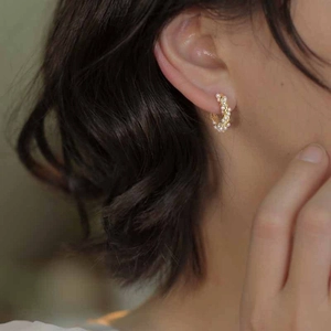 Elegant C-shaped pearl hoop earrings with gold wire wrap on model in close-up view