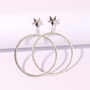 Macro view of silver star earrings with crystal encrusted circular hoop detail