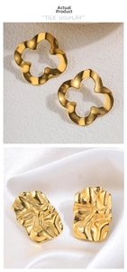 Detail of clover clover and pleated gold earrings on white sand and silk backgrounds