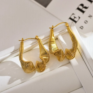 Irregular textured gold hoop earrings with twisted wire design on a white jewelry box