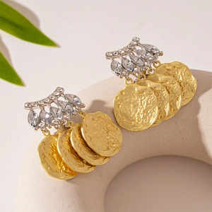Détail de boucles d'oreilles pendantes pièces dorées et base argentée sertie de cristaux