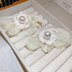 Detailed macro view of white floral earrings with translucent petals and large central pearls