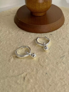 Macro shot of silver sphere dangle earrings featuring minimalist hoop and ball design