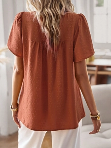 Close-up of reddish-brown short-sleeve top showing textured fabric and back pleat detail