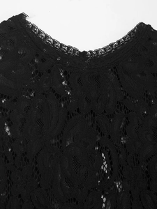 Gros plan sur la dentelle florale noire et les broderies ajourées de la robe midi