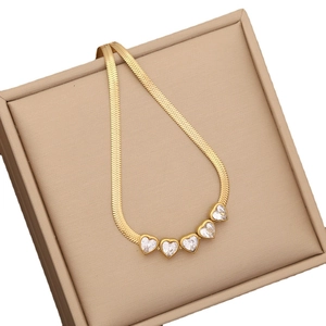 Gold stainless steel snake chain necklace with five heart charms in a beige jewelry box