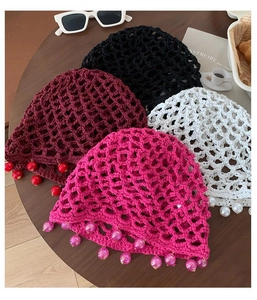 Flat lay of four bohemian hand-woven crochet hats with decorative beads on a wood table