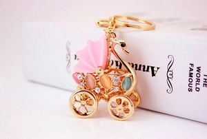 Close-up of golden baby stroller keychain with pink rhinestones and cat eye stones