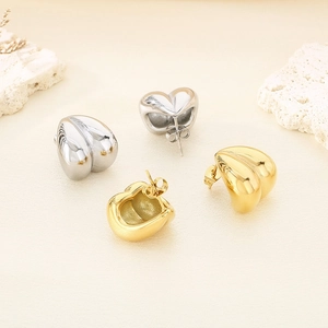 Gros plan de boucles d'oreilles cœur en or 18K et argent polies sur fond minimaliste