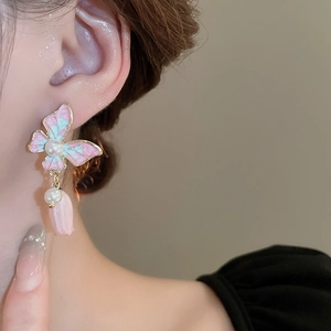 Détail de boucles d'oreilles papillon avec pendentif tulipe et perle sur l'oreille
