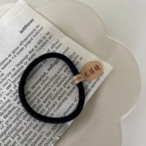 Détail d'un élastique noir sans couture avec étiquette en papier sur une assiette blanche