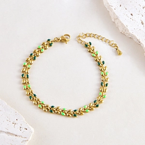 Bohemian gold wheat leaf bracelet with green enamel on a natural stone background