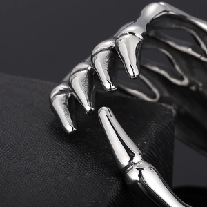 Close-up of vintage silver titanium steel skeleton claw bracelet on a textured background