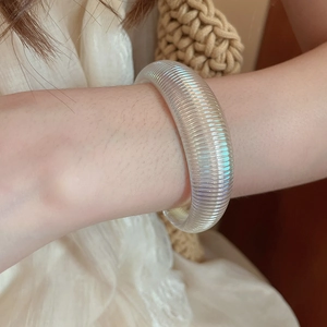 Detailed view of iridescent acrylic geometric bangle with textured horizontal ribbing finish