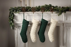 Close-up of knit Christmas stockings in green and cream white with scale texture on a fireplace