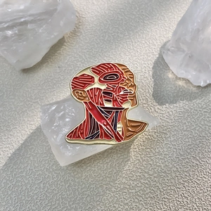 Artistic anatomical head muscle brooch with red enamel and gold-plated metal finish