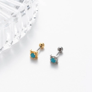 Macro view of gold and silver steel cartilage studs featuring blue round stone settings