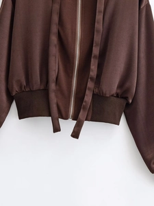 Detail of dark brown satin jacket showing silver metal zipper and ribbed hem