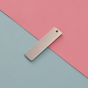 Macro detail of silver rectangular stainless steel tag with mirror finish and pre-drilled hole