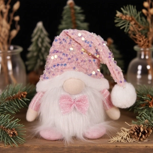 Pink sequin Christmas gnome decoration with white faux fur beard on a wooden table