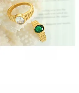 Detail of vintage ribbed 18k gold plated wide rings with white and emerald green stones