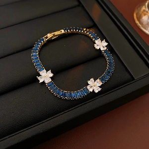 Close-up of golden zircon clover bracelet with blue baguette stones in jewelry box