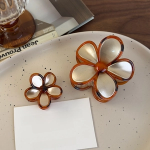 Detail showing vintage amber flower hair claws in two sizes on a decorative plate