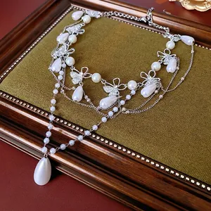 French vintage butterfly necklace with layered waterdrop pearls on a golden antique frame
