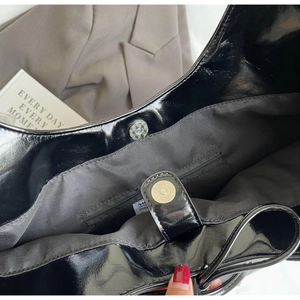 Detail view of the magnetic snap closure and internal zipper pocket on the black leather bag