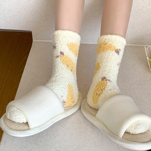 Gros plan de chaussettes épaisses en polaire corail à motif banane et pantoufles blanches