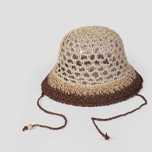 Detail of hollow hand-woven straw hat with contrast trim and tassel tie cord