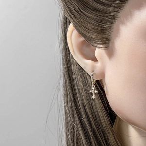 Silver iris cross hoop earrings with central crystal stone shown on a female model