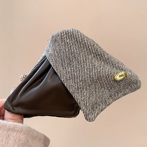 Detail of brown leather and striped fabric claw clip with an oval gold metal plaque