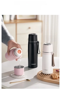 Close-up of insulated stainless steel cup with dual-use lid and portable silicone strap