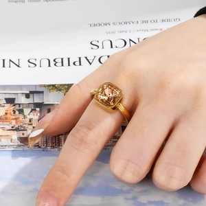 Detail of a gold titanium ring featuring a square champagne zircon worn by a model