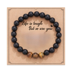 Detail of 8mm matte black beads and tiger eye stones on kraft card packaging