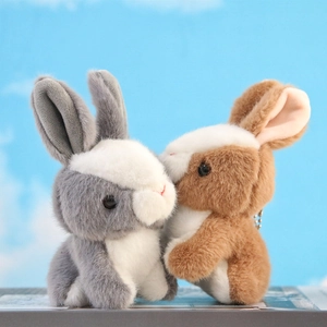 Close-up of grey and brown plush rabbit keychain charms with metal bead chains