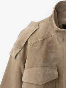 Détails de la veste en daim kaki montrant les coutures fines et les pattes d'épaule