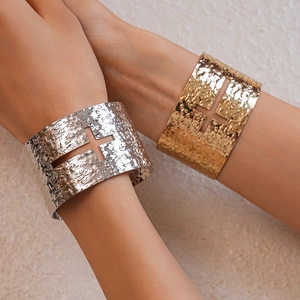 Detail of hammered metal cuff bracelets with hollow cross design in silver and gold finish
