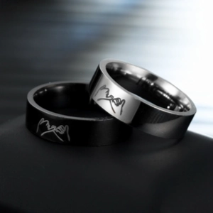 Macro view of couple rings in black and silver featuring engraved pinky swear gesture
