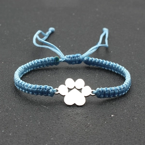 Blue braided rope bracelet with silver dog paw charm on a textured background