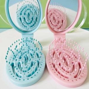 Portable folding hairbrush with mirror in blue and pink, compact design for travel use