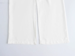 Detailed macro view of white wide-leg pants hem showing smooth fabric and fine stitching