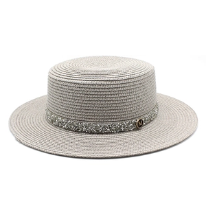 Macro detail of the gray straw sun hat with sparkling rhinestone trim and metal M buckle