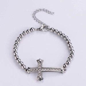 Close-up of silver beaded bracelet with a shimmering pavé cross pendant and lobster clasp