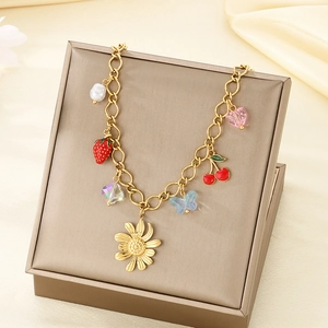 Detail view of gold necklace featuring sunflower strawberry and cherry charms