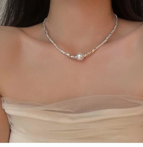 Detail of silver beaded necklace with a central white pearl pendant on the collarbone
